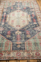 Distressed vintage Sparta rug's geometric plant motifs in denim blue, mint, pale cherry red.