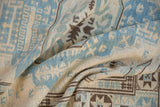 Folded section of Afghani Soumac design carpet with geometric powder blue, ivory, and brown patterns.
