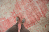 Overhead view of the distressed Oushak carpet's faded red and ivory low-pile texture.
