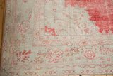 Worn pile showing faded red floral motifs on the corner of a distressed Oushak rug.