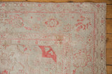 Detail of a distressed Oushak corner with faded rose floral motifs, showing the low-pile texture and secured edge.