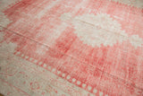 Angled view of the distressed low pile showing faded red abrash on a vintage Oushak carpet.