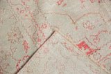 Folded corner of a vintage Oushak carpet revealing its hand-knotted back and distressed pile.