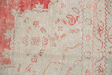 Close-up of the distressed Oushak's low pile showing wear to the knot heads.
