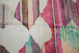 Tiered pink, ivory, and purple striations in the textured weave of a vintage Turkish rag rug.