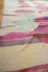 Textured close-up of a hand-woven Turkish rag rug with layered pink, purple, green, and ivory striations.