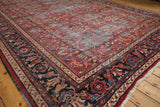 Persian Mahal carpet corner showing brick red field, colorful floral blossom motif, and navy blue border.