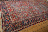 Corner of vintage Mahal rug showing navy border with floral vinery and secure fringe.