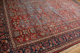 Vintage Mahal carpet's brick red field with allover floral blossom pattern, showing wear.