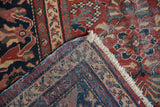 Vintage Mahal rug's folded corner reveals fringe, tightly woven back, and worn brick red floral pattern.