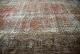Distressed vintage Mahal carpet, visible foundation with faded terra cotta and dusty green floral border.