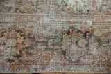 Distressed vintage Mahal carpet close-up, showing worn pile with blush, ivory, and green tones.