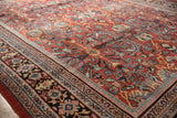 Vintage Mahal rug's navy blue border with blush and sky blue motifs, brick red field.