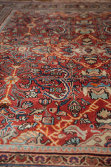 Close-up of vintage Mahal rug pile, sprawling botanical motifs in brick red and blue.