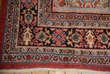 Mahal carpet corner detail: intricate brick red, navy, blush borders, floral patterns, visible knot heads.