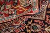 Hand-knotted pile showing scrolled botanical motifs in brick red, navy blue, and sky blue.