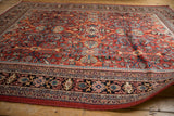 Mahal rug corner, brick red field, sprawling blue botanical patterns, and intricate navy border.