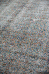 Intricate Herati pattern on distressed Tabriz carpet, featuring worn pale blue and blush textures.