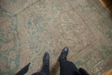 Faded ocean green and ivory floral vinery on distressed Oushak carpet with visible wear.
