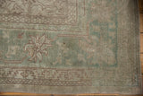 Distressed Oushak rug detail, faded sea foam green field, angular border, and large palmette motif.