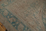 Distressed Oushak border featuring worn ocean green palmettes and soft ivory field.