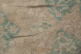 Distressed Oushak pile with even wear, featuring faded seafoam green motifs on pale coffee brown.
