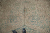 Distressed Oushak carpet texture showing even wear, faded seafoam green, and subtle floral patterns.