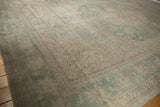Distressed vintage Oushak rug corner showing worn texture, ocean green and ivory palette.