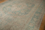 Vintage distressed Oushak showing its meandering vine and palmette border.