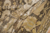Folded vintage Khorassan carpet revealing distressed texture and faded gold floral motifs.