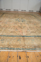 Distressed Tabriz rug end, detailing worn beige pile, blue border, and fringe.