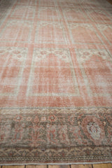 Distressed vintage Oushak rug with paneled blush field and dark ornate border.