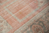 Distressed vintage Oushak rug detail: dusty blush field with worn paneled motifs and grey border.