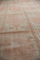 Distressed dusty blush Oushak rug with paneled mini-prayer motifs and visible wear.