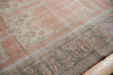 Worn pile of a distressed Oushak rug, displaying dusty blush and beige patterns.