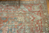 Vintage Heriz carpet pile in faded red, blue-green, and beige motifs.