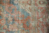 Distressed Heriz rug pile, faded red, teal, ivory floral pattern with visible knot heads.