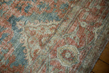 Textured distressed Heriz rug close-up, faded red, blue, and ivory floral pattern.