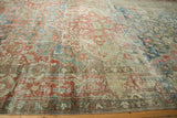 Distressed vintage Heriz carpet, showcasing worn floral patterns in faded sky blue, cherry red, and ivory.
