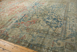 Distressed Heriz carpet surface with faded indigo blue, cherry red, and ivory floral patterns.