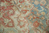 Distressed texture on vintage Heriz carpet, showing faded red, sea foam green floral motifs.