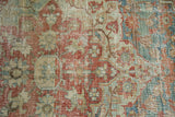 Close-up of distressed Heriz rug: faded red, sea foam, ivory Rococo floral motifs.