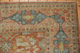Distressed vintage Mahal carpet corner: terra cotta, blue, green floral vinery, visible worn pile.