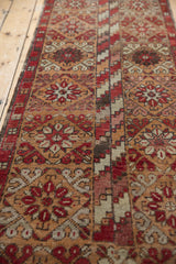 Fragmented Oushak runner's mended seam, revealing varied floral and zig-zag patterns in muted tones.