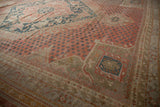 Distressed Oushak carpet with dusty raspberry red field, scattered teal motifs, and corner design.
