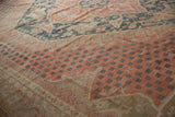 Distressed Oushak carpet with pale raspberry red field and small dark blue motifs.