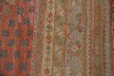 Muted red-orange field with dusty teal motifs and neutral border of a distressed Oushak rug.