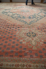Distressed vintage Oushak carpet, pale ruby red field with dusty teal plant motifs.