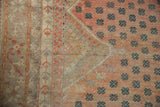 Distressed Oushak carpet detail: faded raspberry field with scattered dusty teal motifs and muted border.