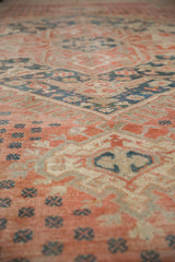 Distressed texture of pale ruby red and teal pinwheel motifs on vintage Oushak rug.